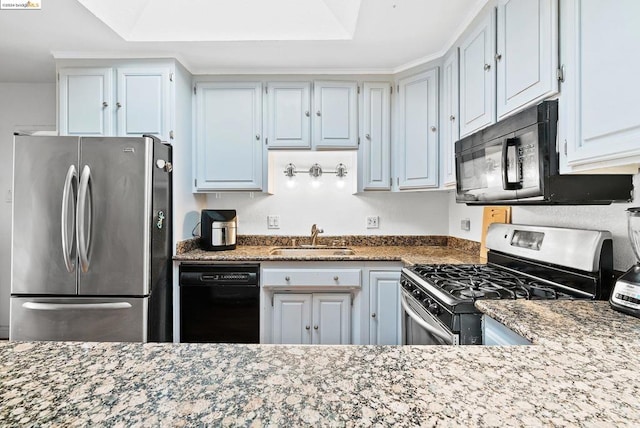 kitchen featuring a raised ceiling, light stone countertops, black appliances, and sink