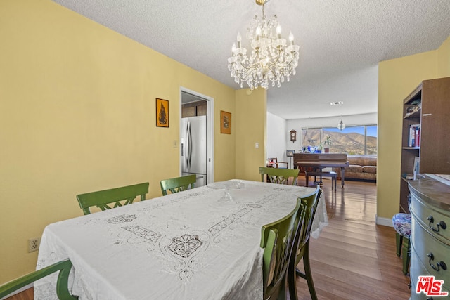 dining area featuring a textured ceiling, an inviting chandelier, and hardwood / wood-style flooring