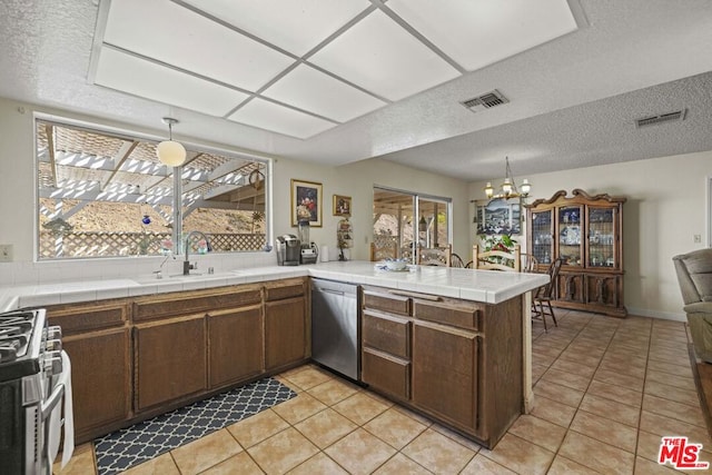 kitchen featuring stainless steel appliances, sink, hanging light fixtures, kitchen peninsula, and dark brown cabinets