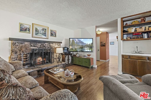 living room with a fireplace, sink, a textured ceiling, and hardwood / wood-style flooring