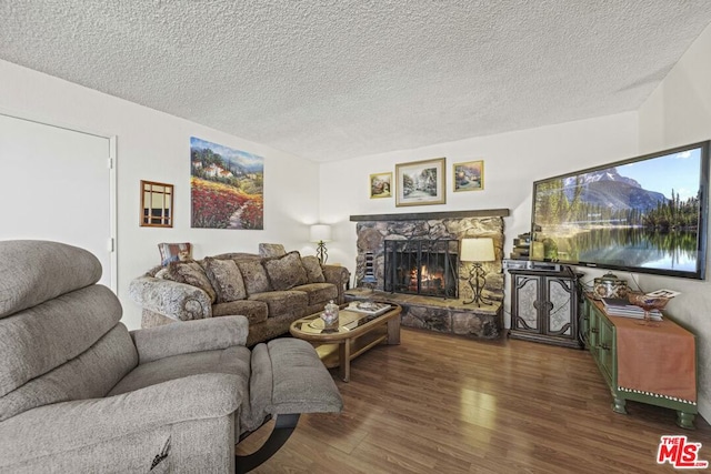 living room featuring a textured ceiling, dark wood-type flooring, and a fireplace