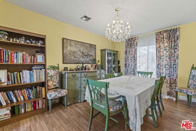 dining space featuring a textured ceiling, a chandelier, and light wood-type flooring