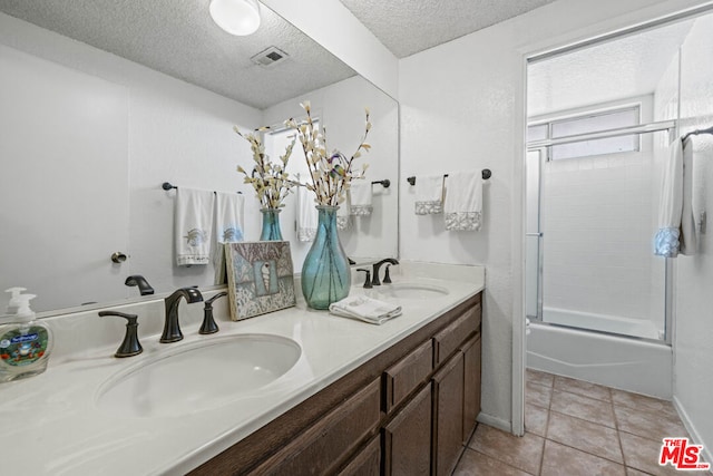 bathroom featuring a textured ceiling, tile patterned flooring, vanity, and shower / bath combination with glass door