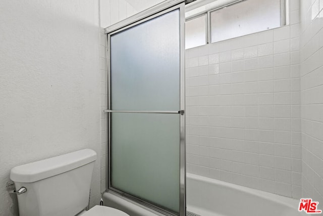 bathroom with toilet and bath / shower combo with glass door