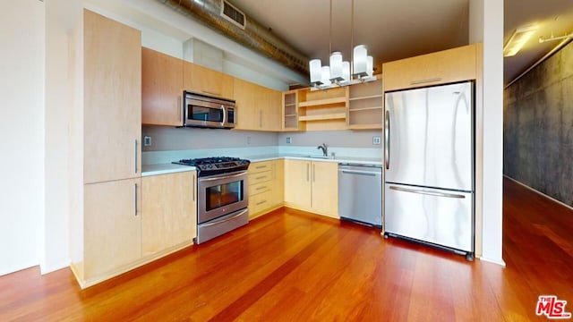 kitchen with sink, light brown cabinetry, decorative light fixtures, wood-type flooring, and stainless steel appliances