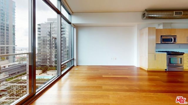 interior space with appliances with stainless steel finishes, light wood-type flooring, and expansive windows