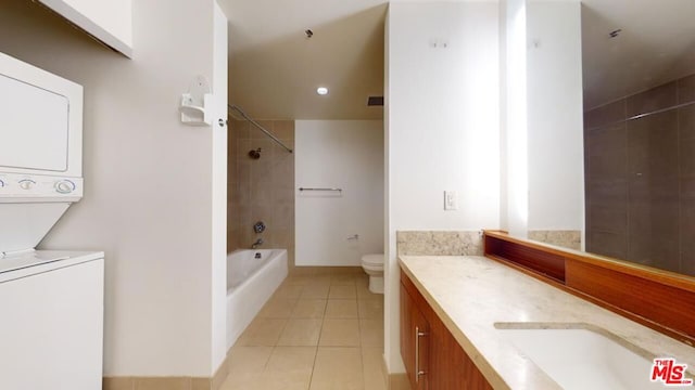 full bathroom featuring stacked washing maching and dryer, tiled shower / bath combo, tile patterned flooring, toilet, and vanity