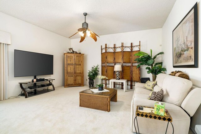 carpeted living room featuring ceiling fan and a textured ceiling