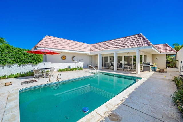 view of swimming pool with area for grilling, a water view, and a patio