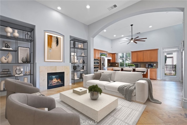 living room featuring a premium fireplace, a towering ceiling, visible vents, and recessed lighting