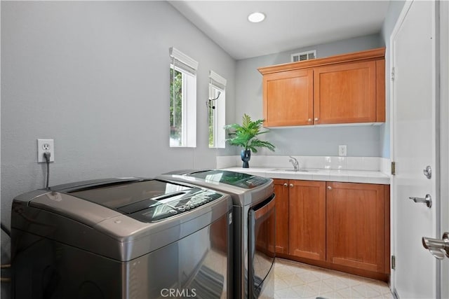 clothes washing area with light floors, cabinet space, visible vents, a sink, and independent washer and dryer