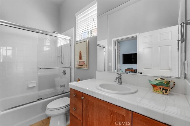 bathroom featuring toilet, shower / bath combination with glass door, and vanity