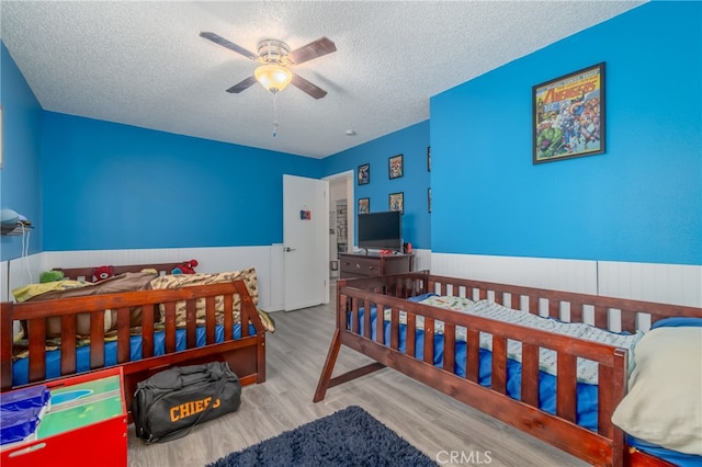 bedroom featuring ceiling fan, a textured ceiling, and light hardwood / wood-style flooring