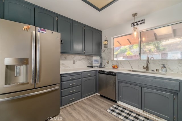 kitchen featuring light hardwood / wood-style flooring, decorative light fixtures, sink, stainless steel appliances, and backsplash