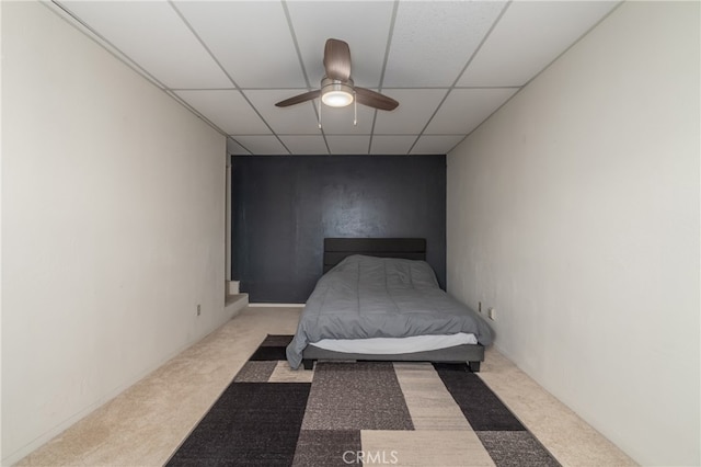 carpeted bedroom with ceiling fan and a paneled ceiling