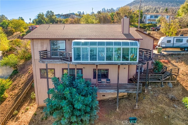 rear view of property featuring a sunroom and a wooden deck