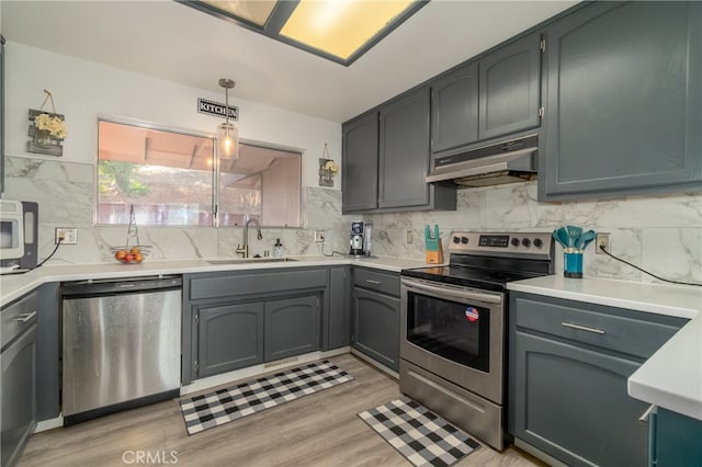 kitchen with pendant lighting, sink, gray cabinetry, appliances with stainless steel finishes, and light hardwood / wood-style floors