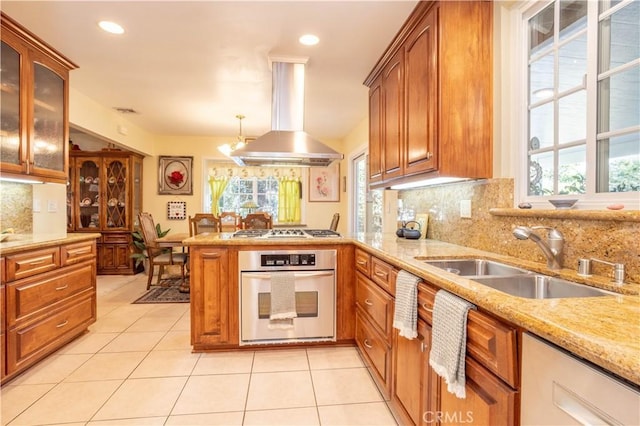 kitchen featuring decorative backsplash, sink, island exhaust hood, hanging light fixtures, and stainless steel appliances