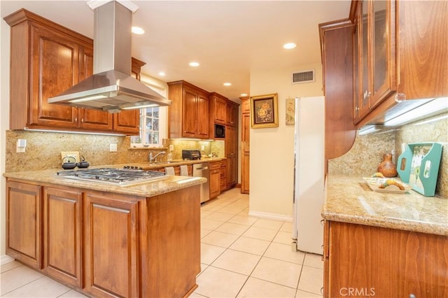 kitchen with stainless steel gas stovetop, light tile patterned floors, light stone counters, island range hood, and white refrigerator