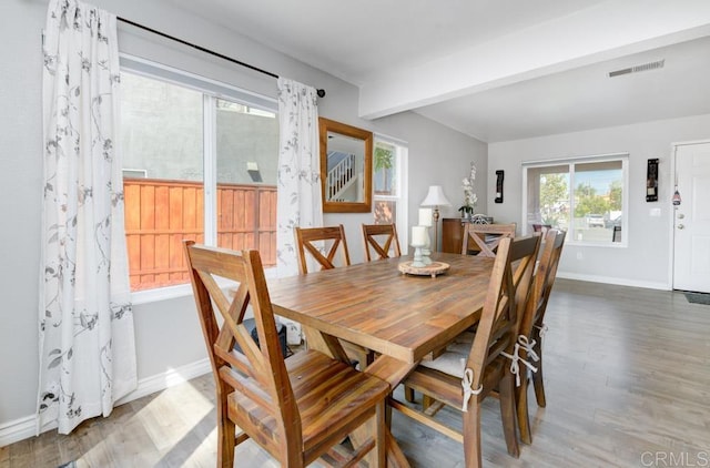 dining space with beamed ceiling and wood-type flooring