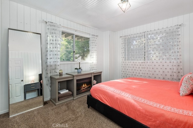 bedroom with a fireplace, carpet, and wooden walls