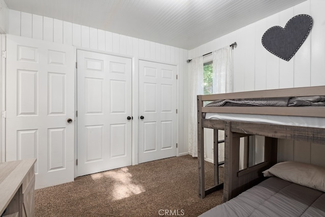 bedroom featuring dark carpet and wood walls