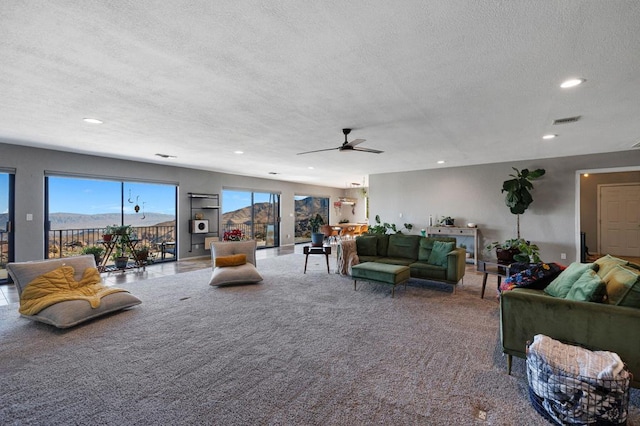 living room with carpet flooring, ceiling fan, a mountain view, and a textured ceiling