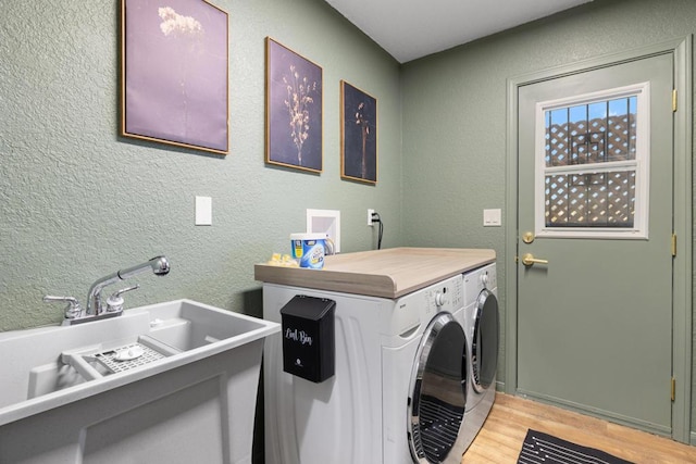 clothes washing area featuring independent washer and dryer, sink, and light hardwood / wood-style flooring