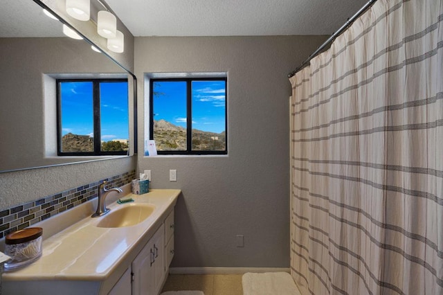 bathroom featuring a textured ceiling, vanity, and backsplash