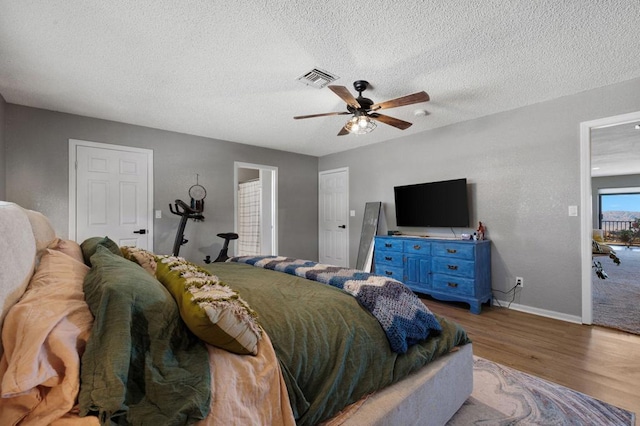 bedroom with ceiling fan, light hardwood / wood-style floors, and a textured ceiling