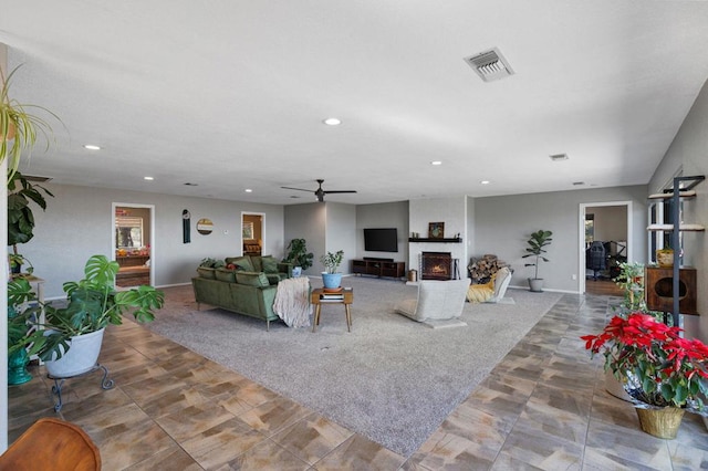 living room with ceiling fan and a fireplace