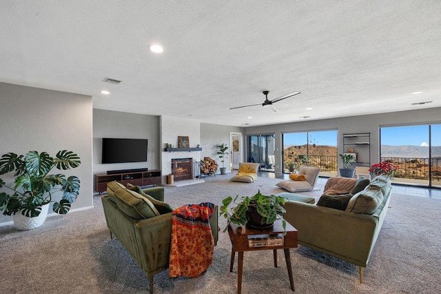 living room featuring ceiling fan, a fireplace, and light carpet