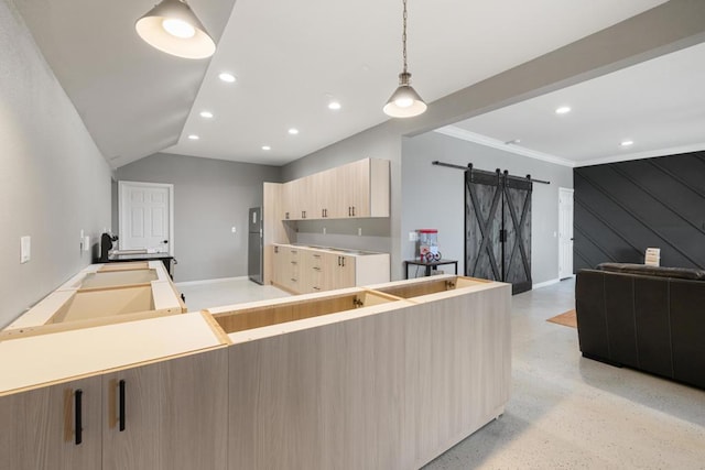 kitchen featuring light brown cabinets, a barn door, crown molding, lofted ceiling, and decorative light fixtures