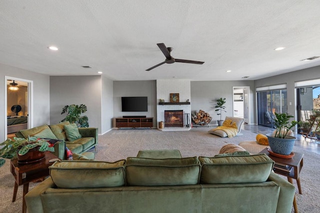 carpeted living room with a textured ceiling, ceiling fan, and a fireplace