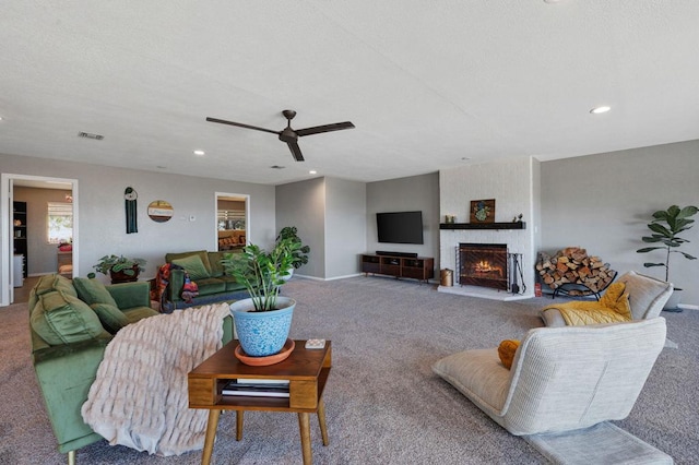 living room featuring ceiling fan, carpet floors, and a fireplace