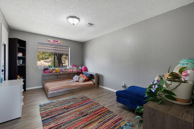 bedroom with hardwood / wood-style floors and a textured ceiling