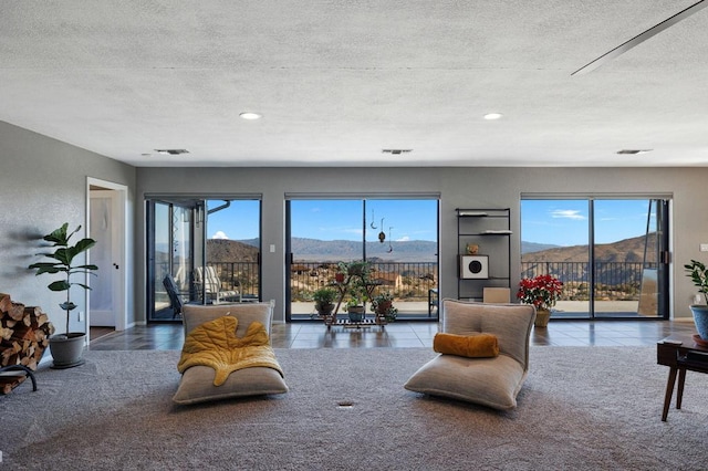 tiled living room featuring a wealth of natural light, a mountain view, and a textured ceiling