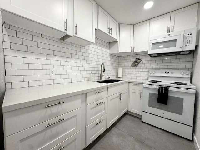 kitchen with tasteful backsplash, white appliances, tile patterned floors, white cabinets, and sink