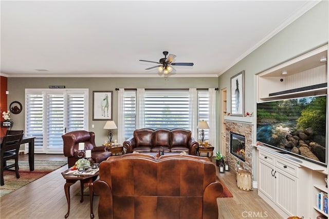 living room with a fireplace, crown molding, light wood-type flooring, and ceiling fan