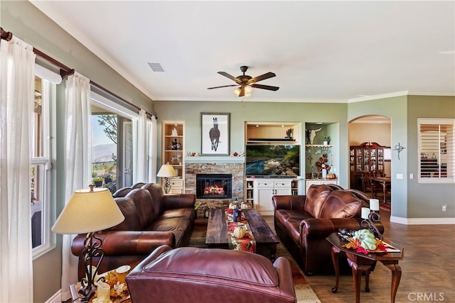 living room featuring ceiling fan, a fireplace, crown molding, and wood-type flooring