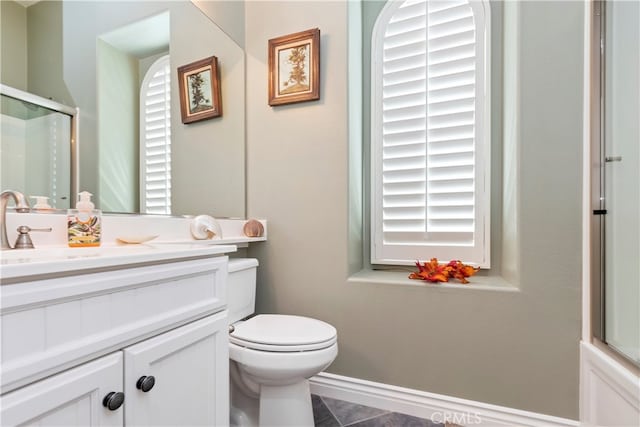 bathroom with toilet, tile patterned flooring, vanity, and a shower with shower door