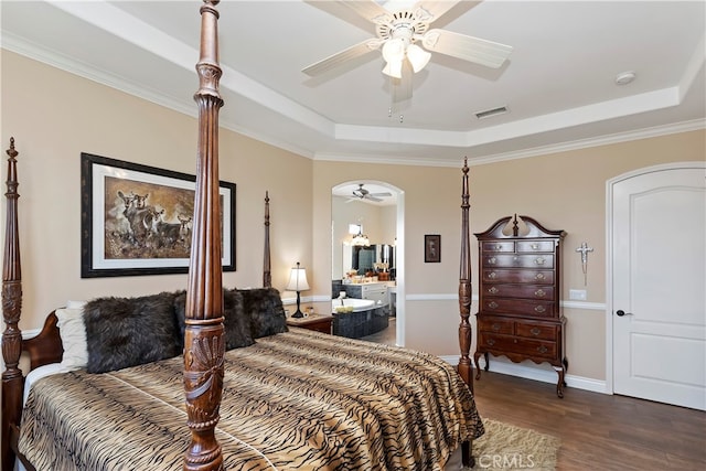 bedroom with ceiling fan, a raised ceiling, ornamental molding, ensuite bathroom, and dark hardwood / wood-style flooring