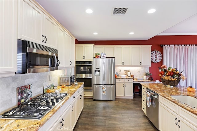 kitchen featuring light stone counters, ornamental molding, backsplash, stainless steel appliances, and dark hardwood / wood-style flooring