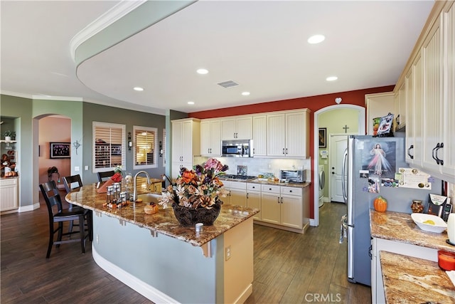 kitchen with stainless steel appliances, a kitchen bar, dark hardwood / wood-style flooring, and light stone counters