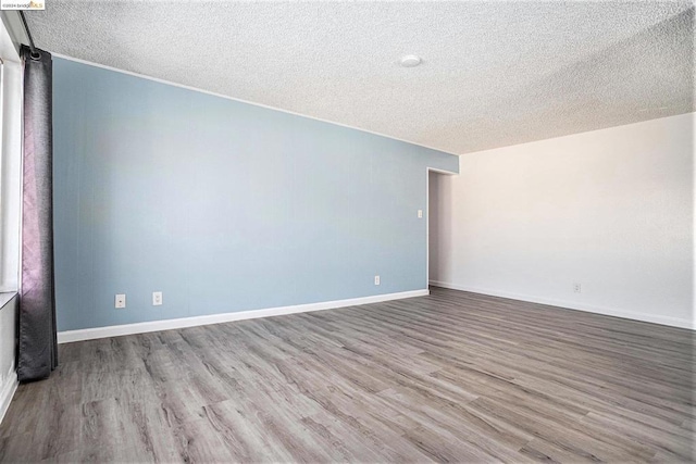 spare room with light wood-type flooring and a textured ceiling