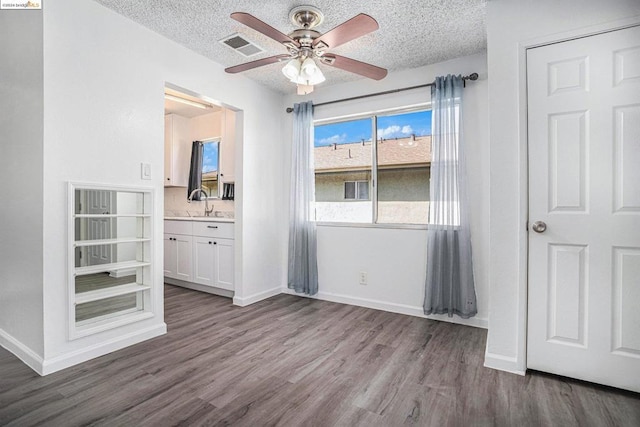 interior space with a textured ceiling, dark hardwood / wood-style floors, and ceiling fan