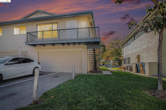 view of front facade featuring a yard, a balcony, and a garage