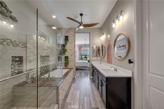 bathroom with hardwood / wood-style flooring, ceiling fan with notable chandelier, independent shower and bath, and vanity