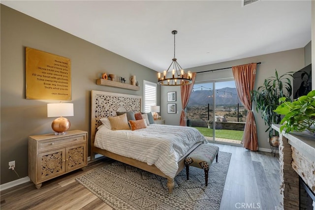 bedroom featuring access to exterior, a mountain view, an inviting chandelier, and multiple windows