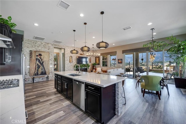 kitchen featuring a center island with sink, decorative light fixtures, sink, and appliances with stainless steel finishes